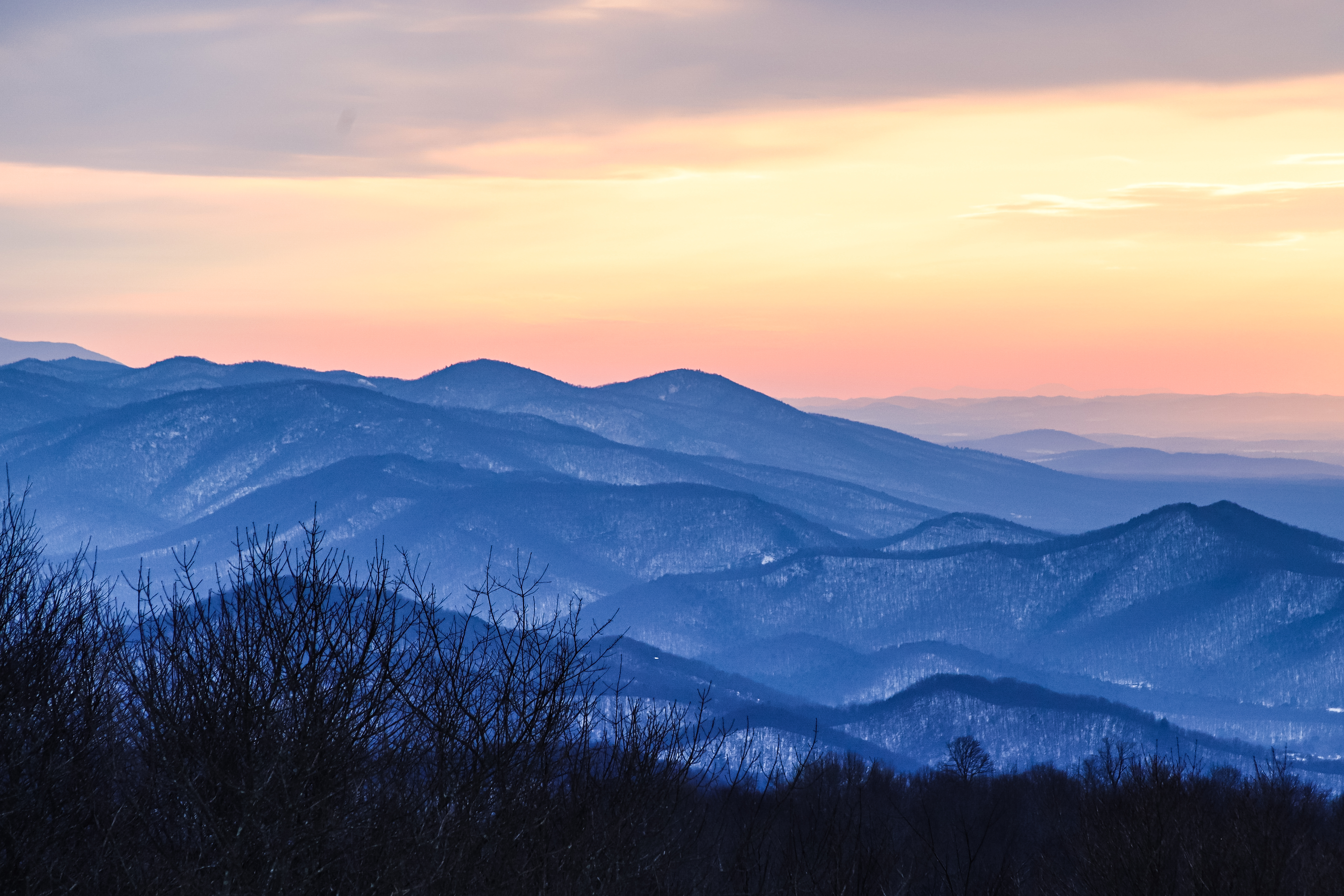 Snow-dusted Blue Ridge Mountains layered at sunset with warm pink and orange winter sky viewed from Skyline Drive